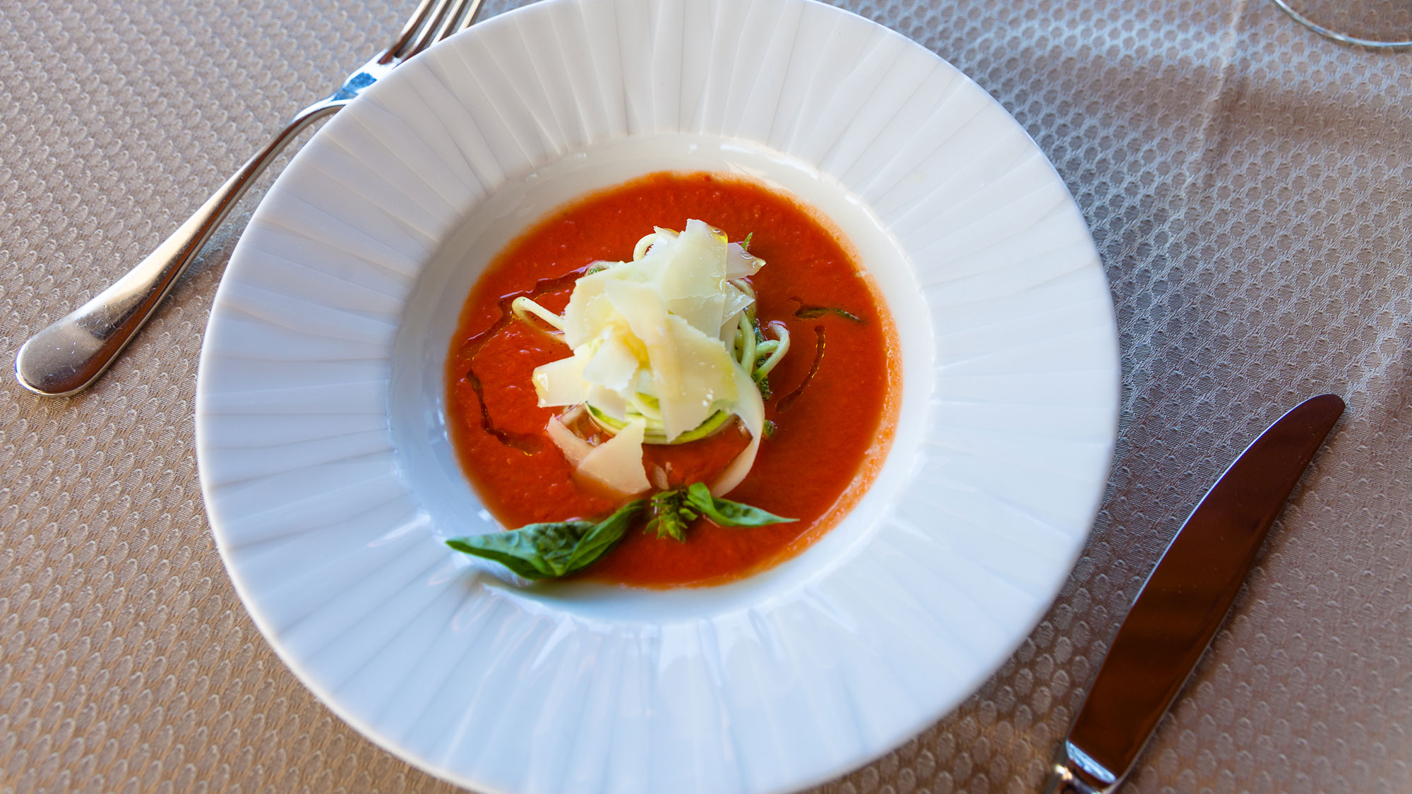 Gazpacho of tomato and cucumber with zucchini spaghetti, basil and shaved parmesan